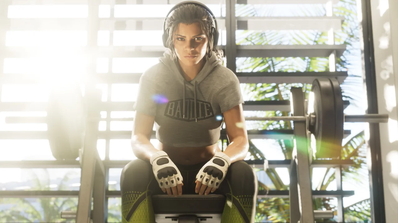 Lucia Caminos wearing headphones and training gloves, seated in a gym in an official GTA 6 screenshot.